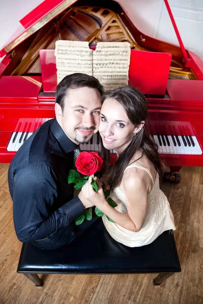 Pasangan dengan mawar di dekat piano merah — Stok Foto