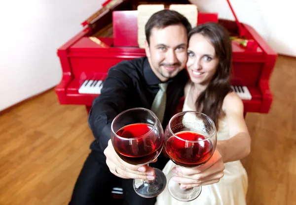 Couple with glasses of wine near piano — Stock Photo, Image