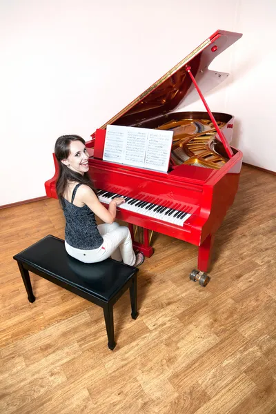 Женщина играет на красном рояле — стоковое фото