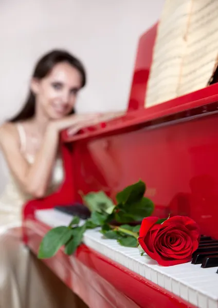 女性と赤いピアノに赤いバラ — ストック写真