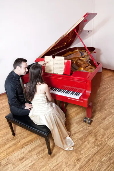 Пара, играющая на красном пианино — стоковое фото