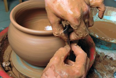 Bir çömlekçinin elleri, çemberin üzerinde toprak kavanozu yaratıyor.