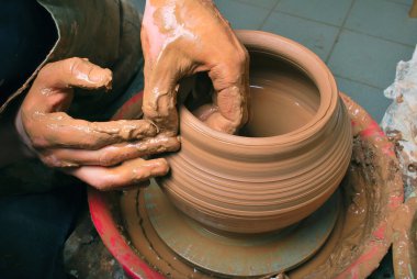 Hands of a potter, creating an earthen jar on the circle clipart