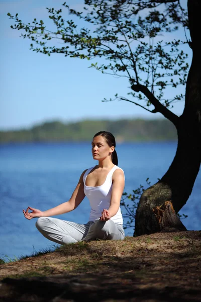 Flicka tränar yoga på bryggan nära lake — Stockfoto