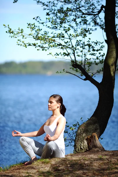 Menina treina ioga no cais perto do lago — Fotografia de Stock