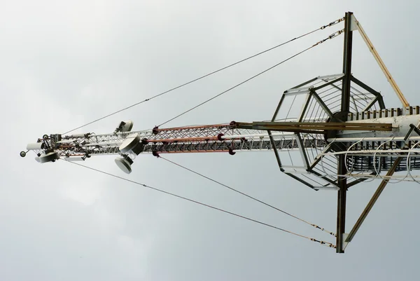 stock image A metal frame telecommunication tower with transmission dish standing agai