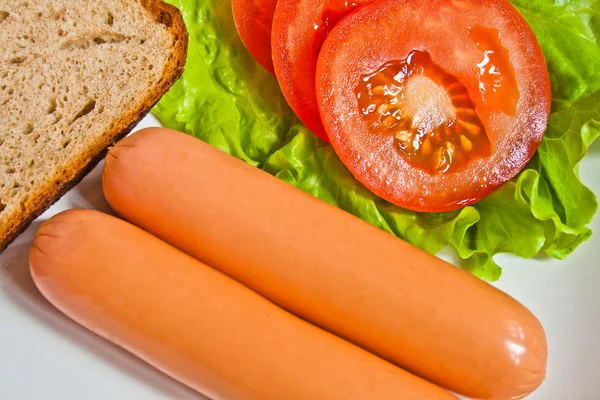 Sausage on green lettuce with bread and tomato — Stock Photo, Image