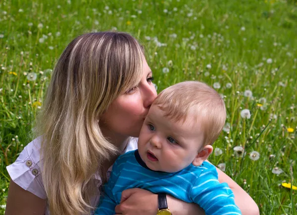 Jovem mãe beija seu filhinho — Fotografia de Stock