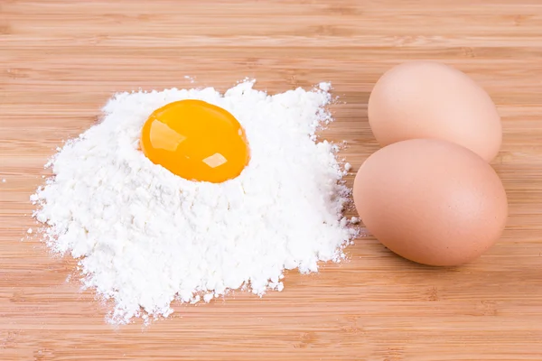 Yolk and eggs of house hens with wheat flour on kitchen to a board — Stock Photo, Image