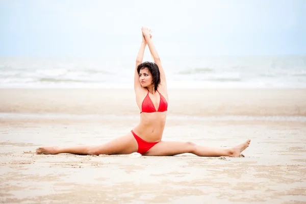 Όμορφη γυναίκα που κάνει άσκηση γιόγκα στην παραλία — Φωτογραφία Αρχείου