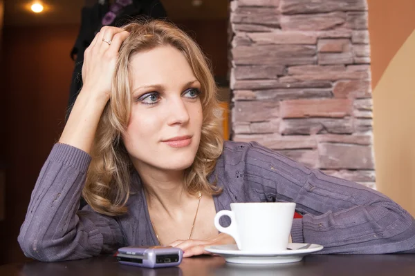 Ung blondin i ett café som väntar på ett samtal — Stockfoto