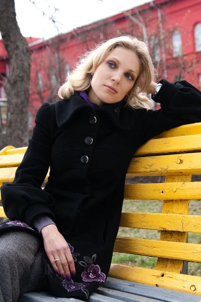 Smutny Młoda blondynka siedzi na ławce w parku — Zdjęcie stockowe