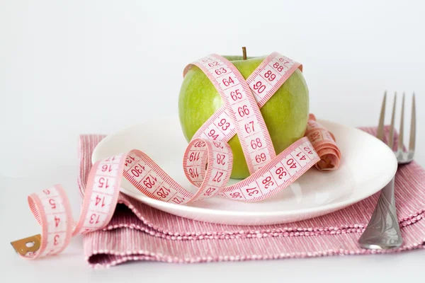 Pomme verte et ruban à mesurer sur une assiette blanche — Photo