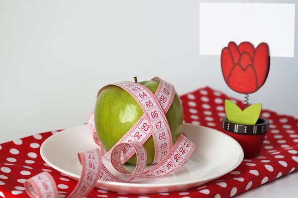 Manzana verde y cinta métrica en un plato blanco y alfiler con una hoja blanca o —  Fotos de Stock