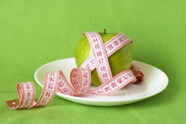 Apel hijau dan pita pengukur di piring putih — Stok Foto
