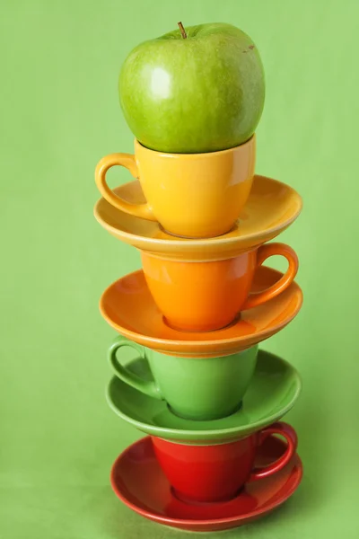 Grönt äpple och ljusa koppar på en grön bakgrund — Stockfoto