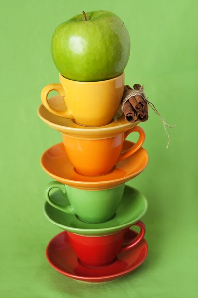 Zelené jablko a světlé poháry na zeleném pozadí — Stock fotografie