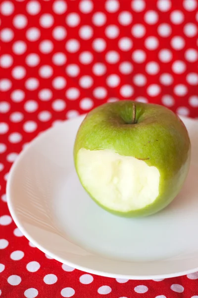 Green apple on a white plate on a red background — Stock Photo, Image