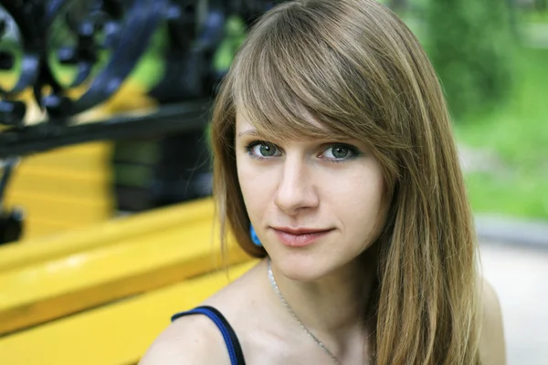 Portret młodego piękna blondynka w żółty ławce w parku — Zdjęcie stockowe