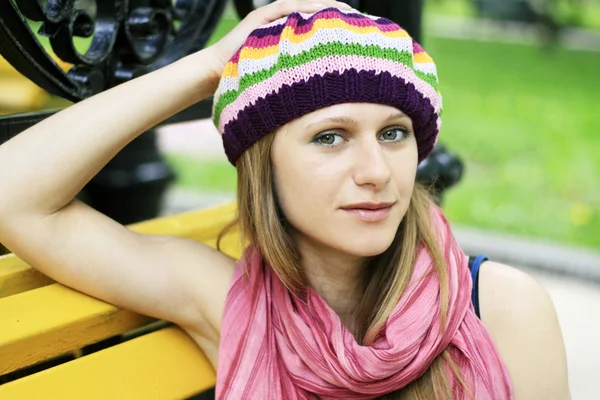 Portræt af en ung smuk blondine i gul bænk i parken - Stock-foto