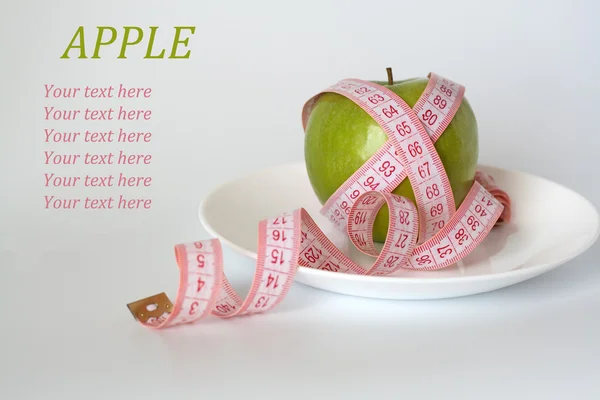 Yeşil elma ve beyaz bir plaka üzerinde ölçüm bandı — Stok fotoğraf