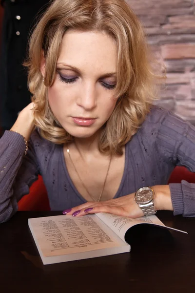 Porträt eines jungen hübschen Mädchens im Café mit einem Buch — Stockfoto