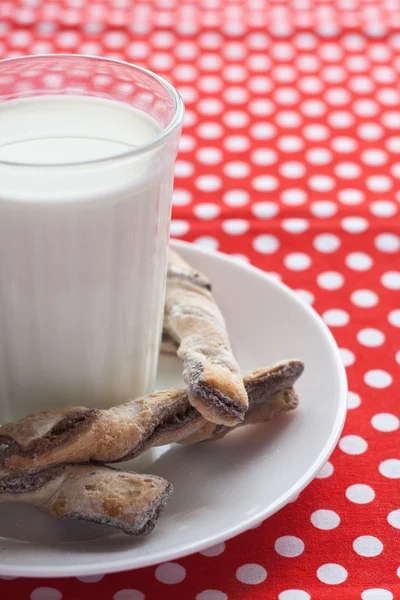 Ein Glas Milch und leckere Kekse auf einem weißen Teller — Stockfoto