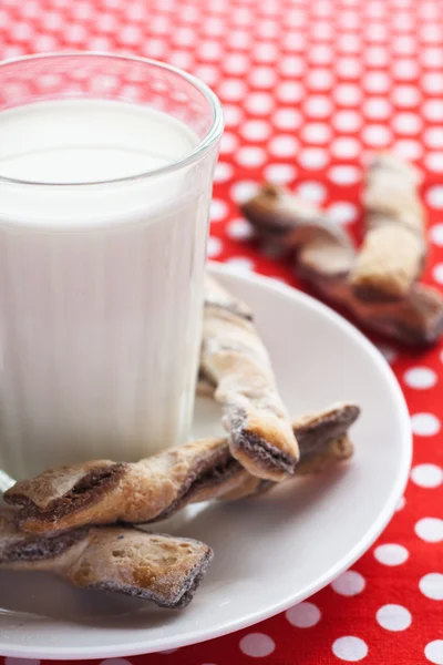 Een glas melk en lekkere koekjes op een witte plaat — Stockfoto