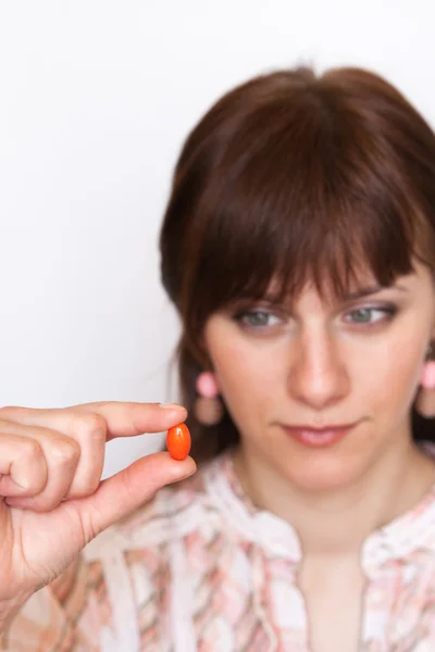 O fată tânără care deține o pastilă portocalie — Fotografie, imagine de stoc