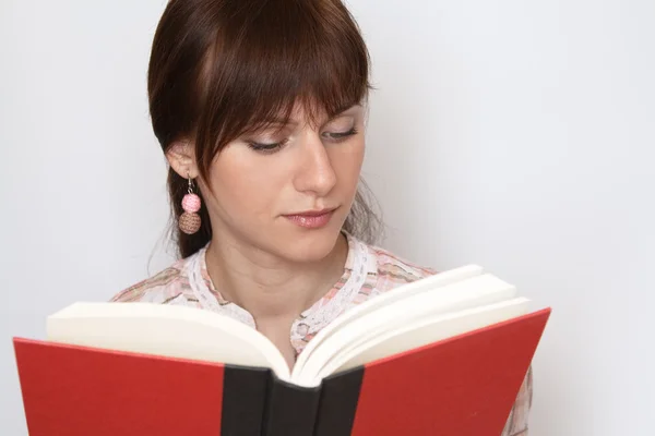 Jovem bela morena lendo um livro vermelho — Fotografia de Stock