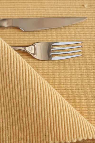 Forchetta in metallo e coltello appoggiati su una tovaglia gialla — Foto Stock
