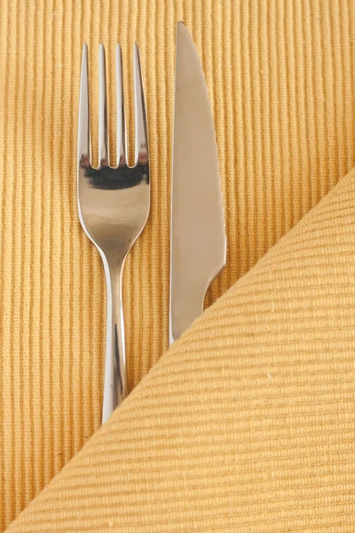 Metallgabel und Messer liegen auf einer gelben Tischdecke — Stockfoto