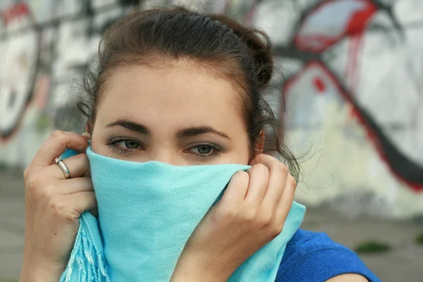 stock image Young beautiful brunette hiding behind a blue scarf