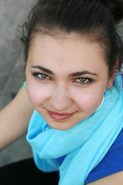 Portret van een mooie jonge brunette in een blauwe sjaal — Stockfoto