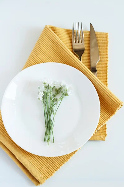 Tenedor, cuchillo, plato y pequeñas flores blancas — Foto de Stock
