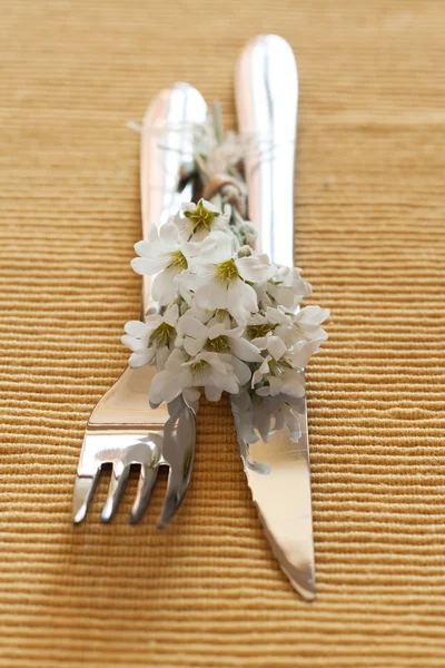 Garfo, faca e um pequeno buquê de flores brancas — Fotografia de Stock