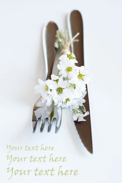 Fourchette, couteau et un petit bouquet de fleurs blanches — Photo