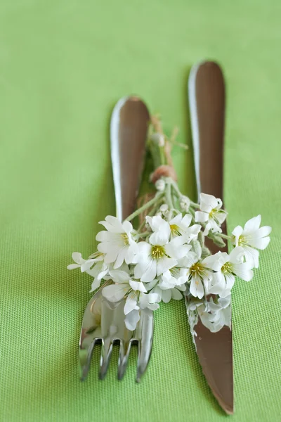 Gaffel, kniv och en liten bukett med vita blommor — Stockfoto