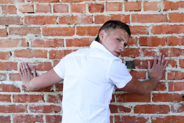 Pohledný mladý muž opřený cihlová zeď — Stock fotografie