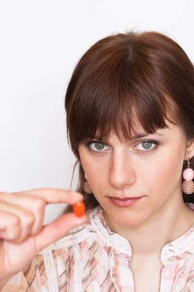 Tineri frumos bruneta holding an portocaliu pilula — Fotografie, imagine de stoc