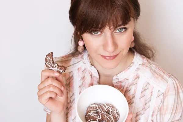 Young beautiful brunette eating tasty chocolate cookies — Stock Photo, Image