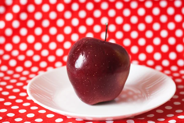 Rött saftigt äpple på en vit platta — Stockfoto