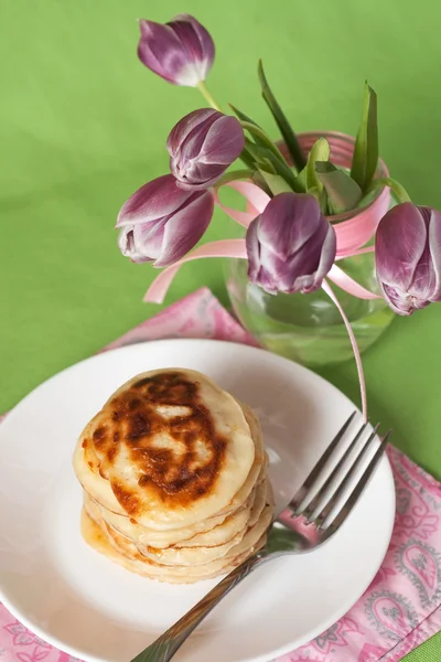 Deliziose frittelle per colazione e un vaso con un bouquet di tulipani — Foto Stock