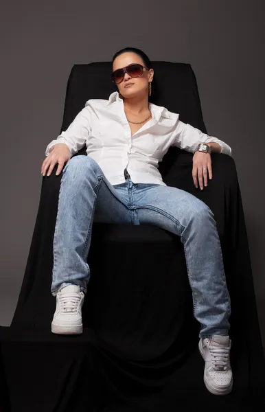Junges Mädchen wie Tomboy sitzt auf schwarzem Stuhl — Stockfoto