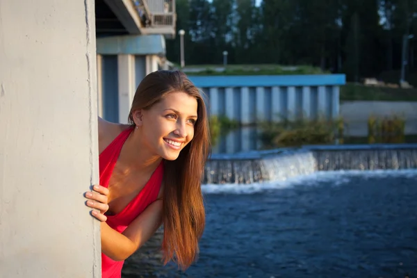 Piękna młoda kobieta w czerwonym uśmiech i spojrzenie na zachód słońca — Zdjęcie stockowe