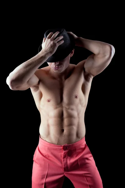 Hombre atlético posando desnudo en la oscuridad con sombrero — Foto de Stock