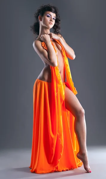 Skönhet naken dansare poserar i orange slöja — Stockfoto