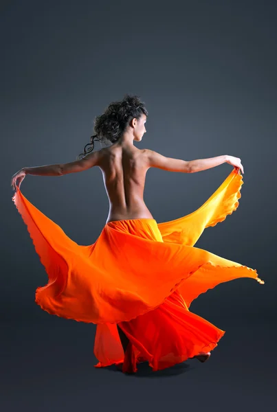 Красуня дівчина з голим хребтом танцює в помаранчевій тканині — стокове фото