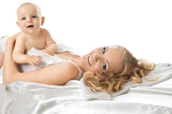 Hübsches Baby sitzt auf Mama im Seidenbett — Stockfoto