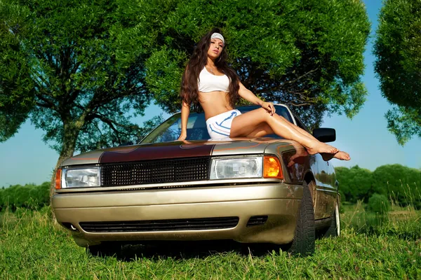 Молодая красавица моет машину на летнем закате — стоковое фото
